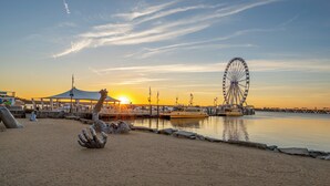 Een strand met een reuzenrad op de achtergrond, een tent en een standbeeld.