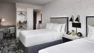 A hotel room with two beds, a desk, a chair, and a wardrobe.