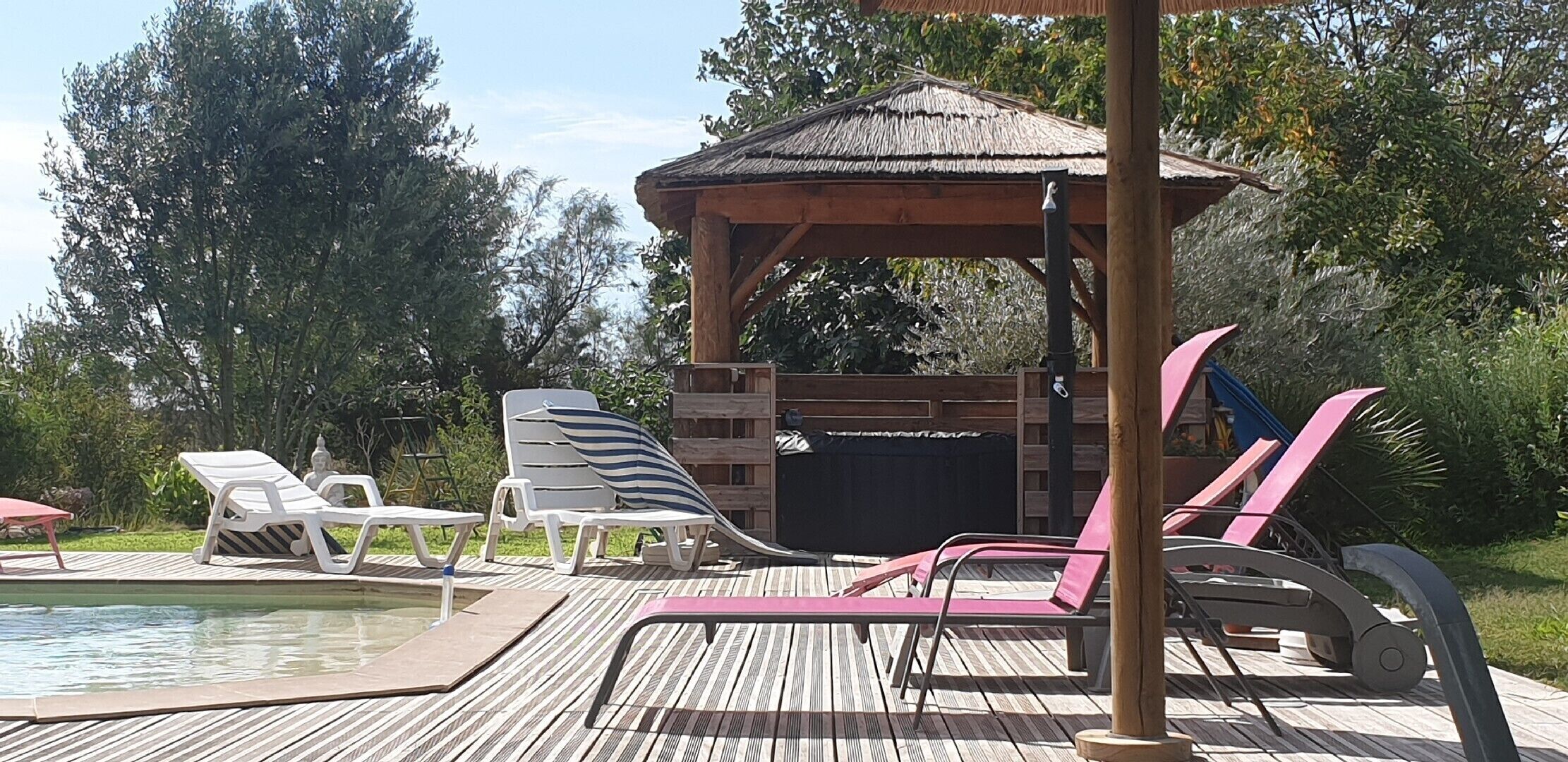 A wooden deck with lounge chairs and a pool.