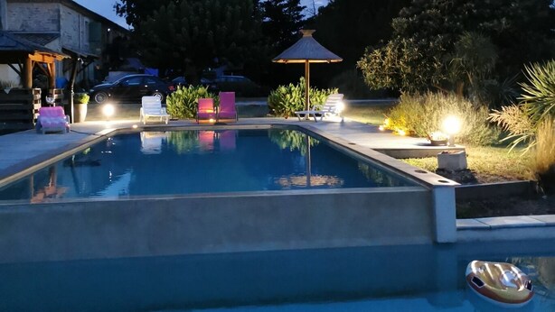 Une piscine avec des chaises longues et un kiosque.