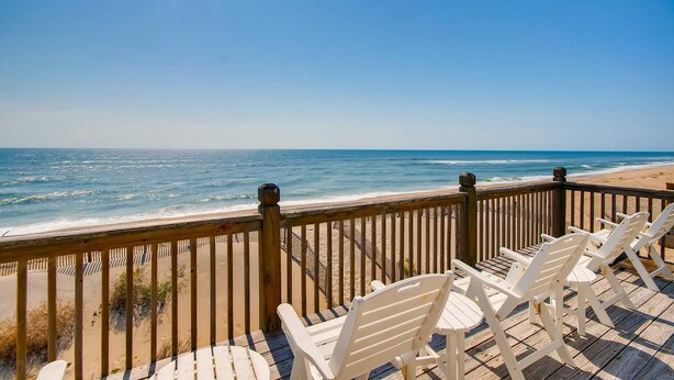 A wooden deck with white chairs overlooking a beach. - Premier Oceanfront w/ Private Pool, Hot Tub, Elevator, Sauna, Theater, Game Room (Avon)
