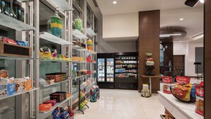 A well-organized store with shelves stocked with snacks, a refrigerated section, and a variety of packaged goods.