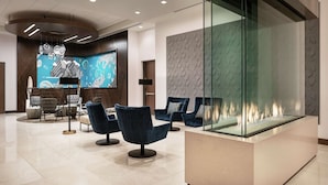 A modern lobby with a glass fireplace, comfortable seating, and a contemporary art piece.