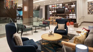 A modern living room with a sofa, armchairs, a coffee table, and a bookshelf.