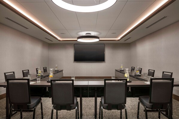 A conference room with a long table, chairs, a flat-screen TV, and a ceiling light fixture. - Home2 Suites by Hilton Denver Downtown Convention Center (Denver)