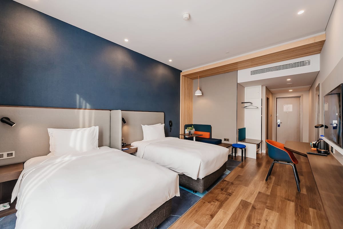 Una habitación de hotel moderna con dos camas, un escritorio y una silla.