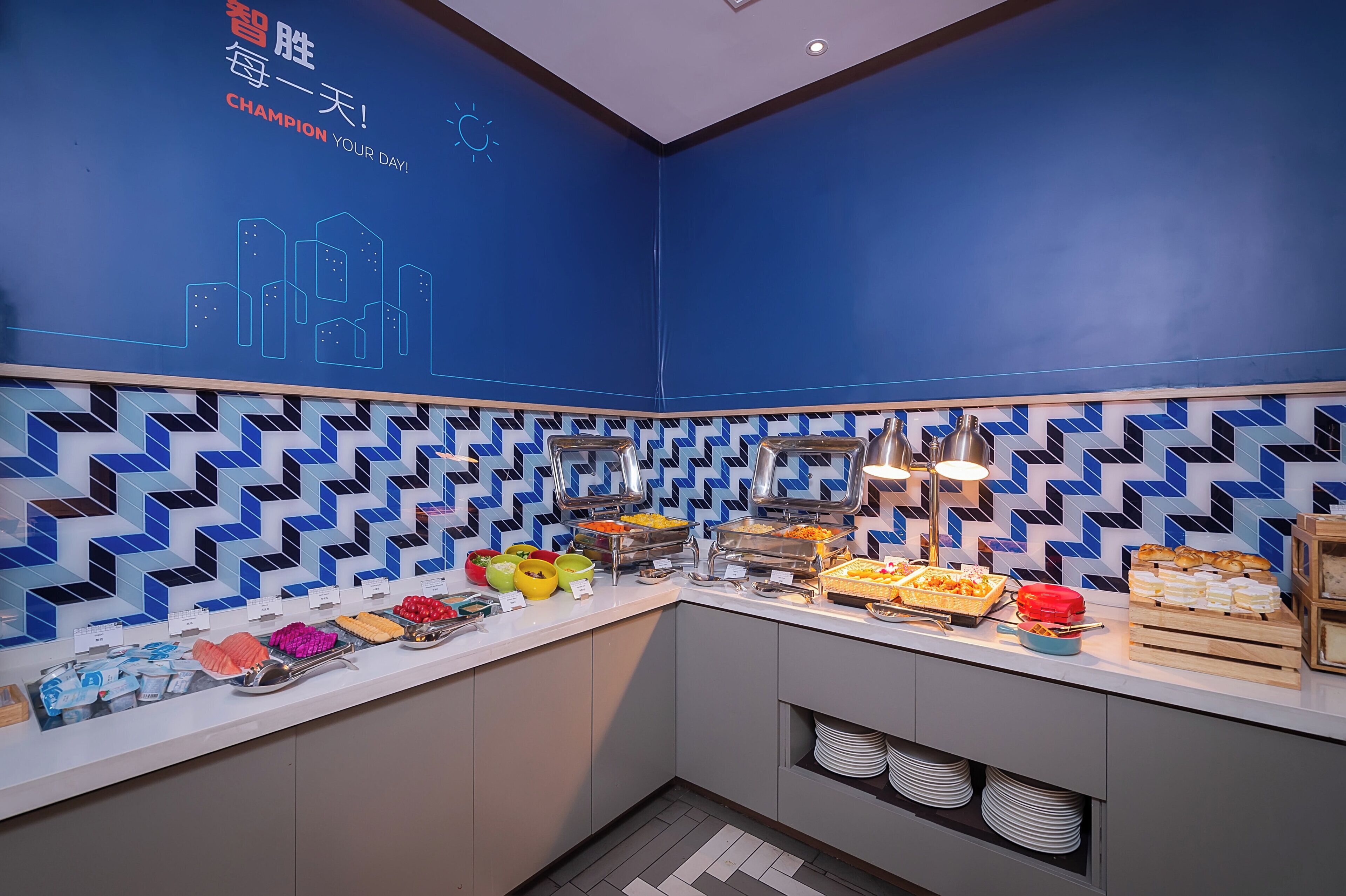 A buffet setup with various food items and a blue patterned wall.