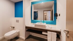 A modern bathroom with a white toilet, a sink with a blue-tiled backsplash, and a mirror. - Holiday Inn Express Taizhou CMC by IHG (Taizhou)
