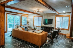 A living room with a sofa, chairs, a television, and a fireplace.