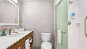 A modern bathroom with a white sink, toilet, and shower area.