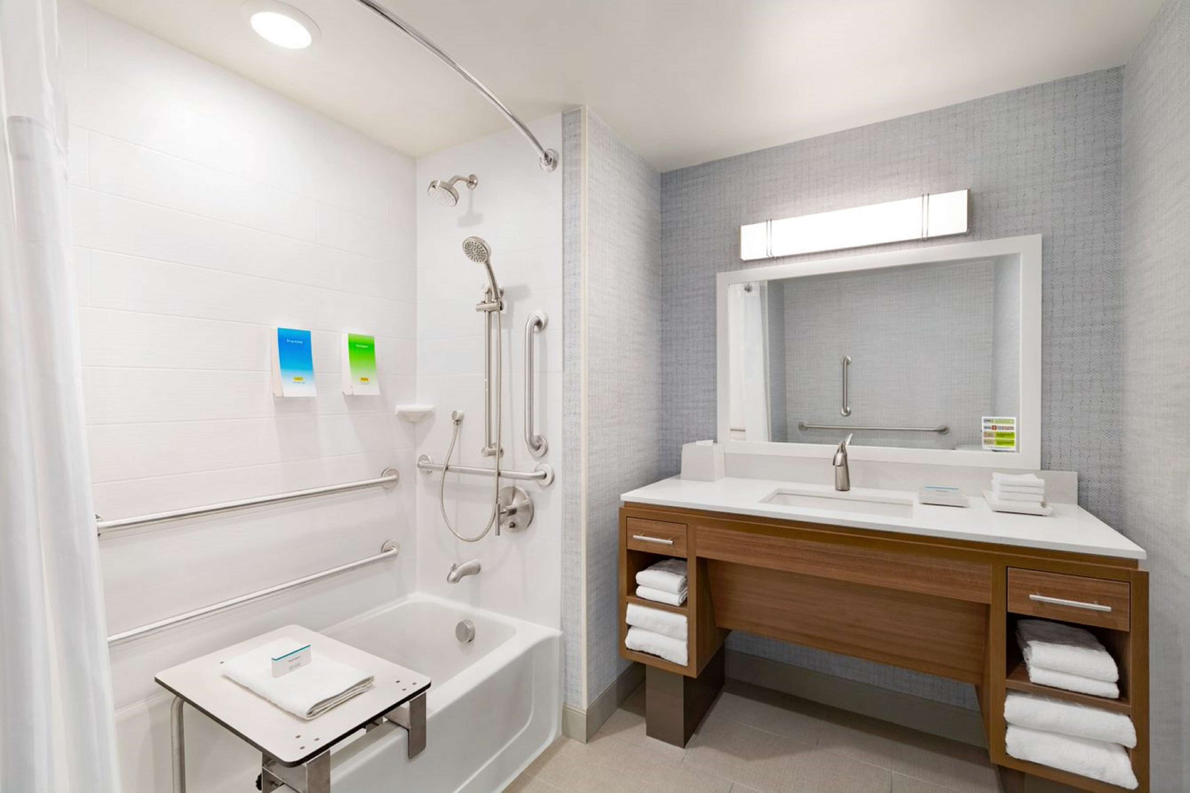 A modern bathroom with a bathtub, shower, and vanity with a mirror.