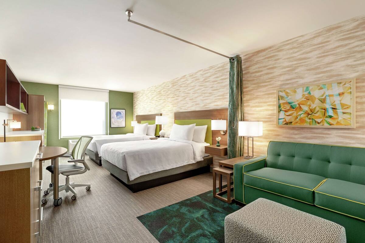 Een hotelkamer met een bed, een groene bank, een bureau en een stoel.