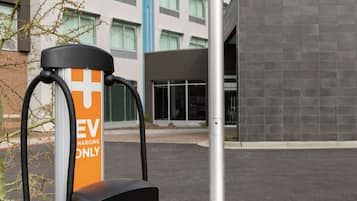 Una estación de carga para vehículos eléctricos frente a un hotel con el letrero 'Home 2'.