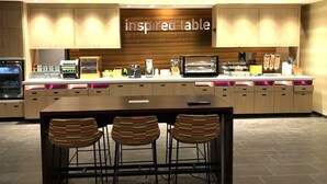 A modern kitchen with a central island, bar stools, and a sign that reads "inspired table". - Home2 Suites by Hilton Scottsdale Salt River (Scottsdale)