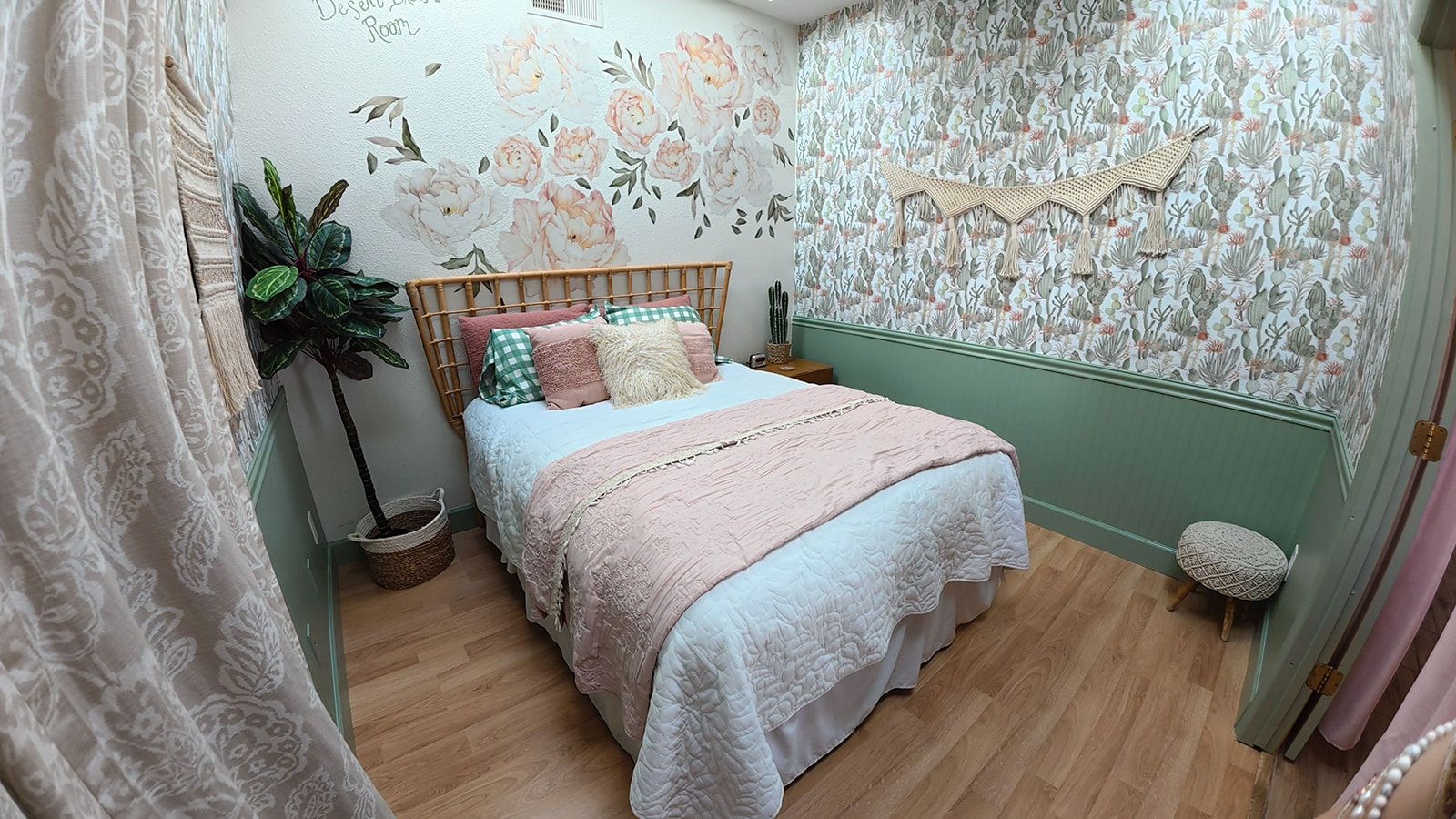 A bedroom with a bed, a potted plant, and a wall with floral wallpaper.
