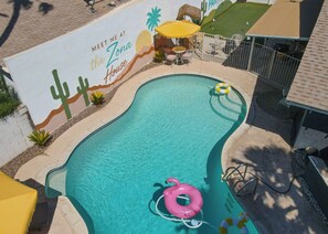 A swimming pool with a mural, a pink flamingo float, and a yellow umbrella.