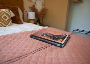 Een boek met de titel 'Art of the Boot' op een bed met een roze quilt.