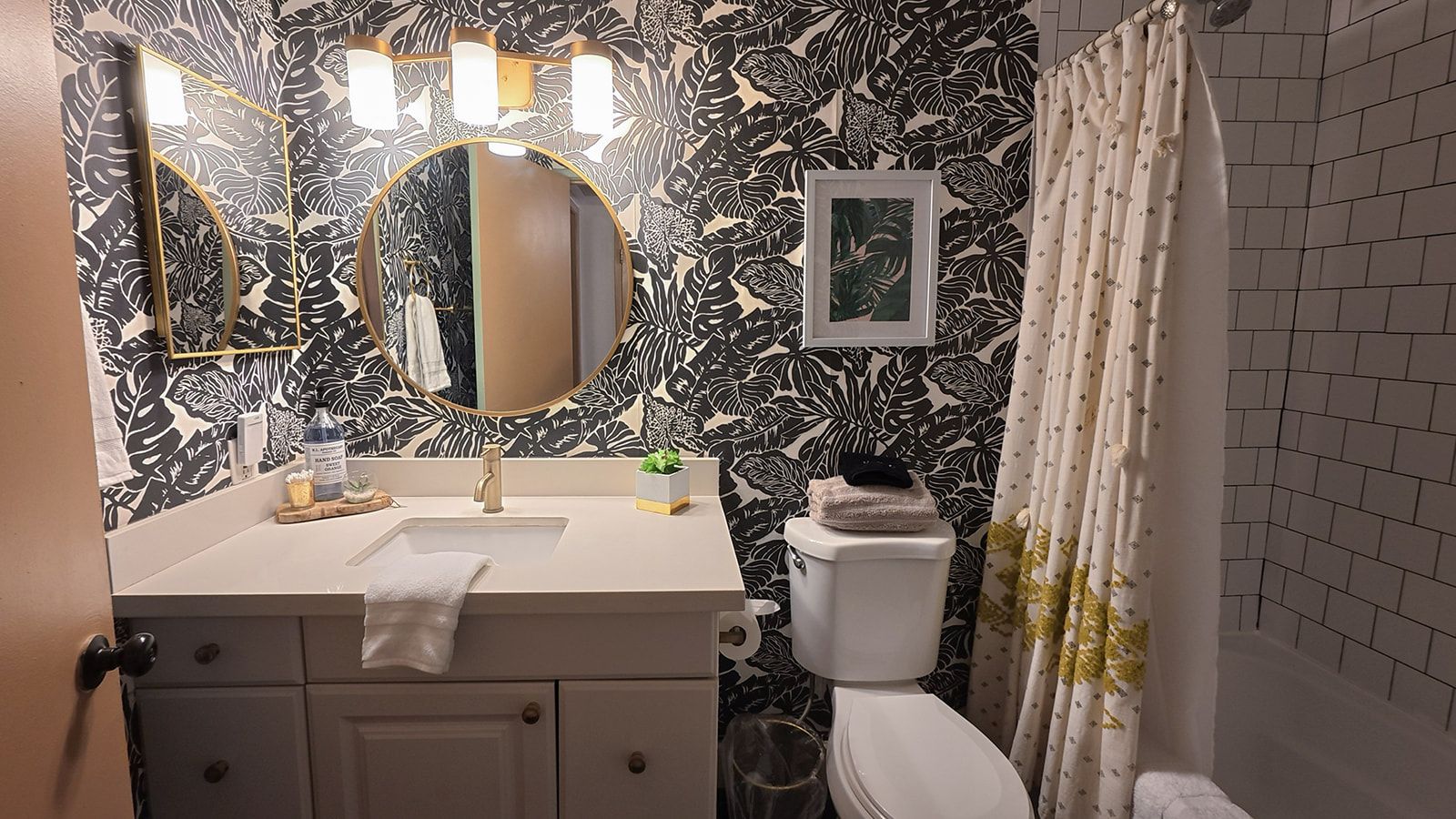A bathroom with a white sink, a mirror, a toilet, and a shower curtain.