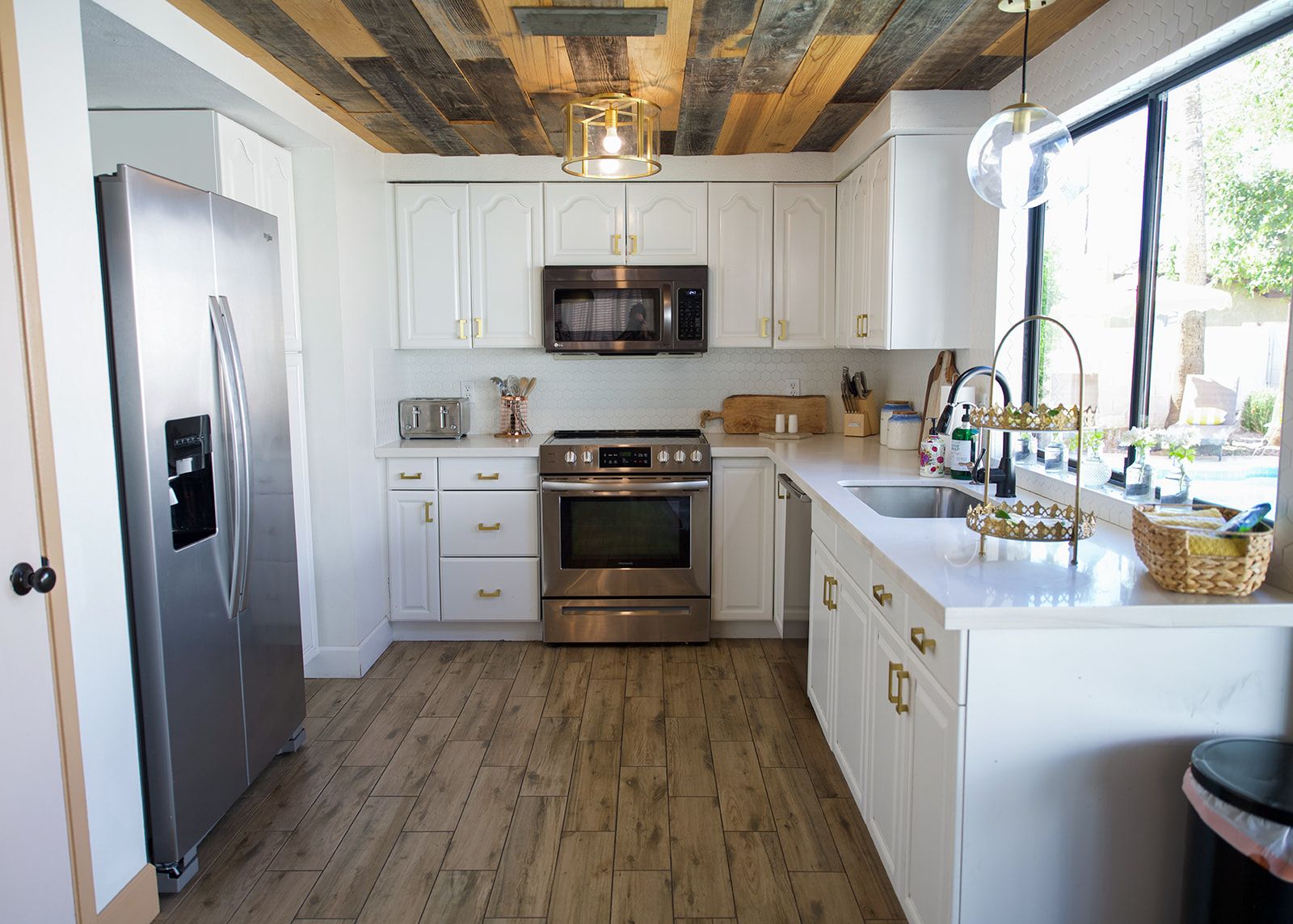 A kitchen with white cabinets, stainless steel appliances, and a wooden floor.