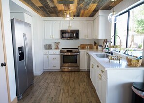 Cocina con armarios blancos, electrodomésticos de acero inoxidable y piso de madera.