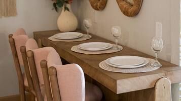 A wooden dining table with a vase of flowers and two mirrors on the wall.