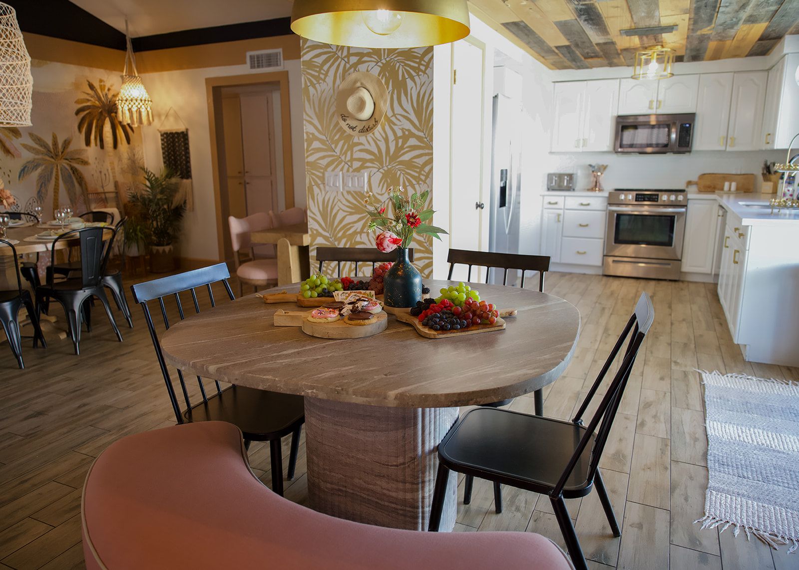 A dining area with a round wooden table, black chairs, and a central vase with flowers.