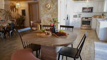 A dining area with a round wooden table, black chairs, and a central vase with flowers.