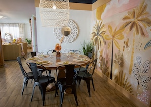 A dining area with a round table set for four, surrounded by black chairs.