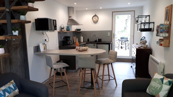 A modern kitchen with a central island, bar stools, and a dining area with a table and chairs.