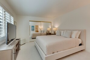 Un dormitorio moderno con una cama grande, un televisor sobre un mueble y un espejo.