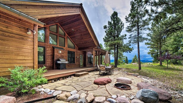 Une cabane en rondins avec un patio en pierre, un espace salon extérieur et une vue sur les montagnes.