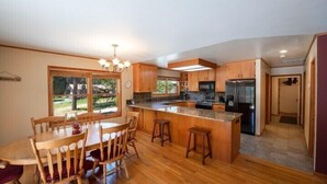 A modern kitchen with wooden cabinets, a central island, and a stainless steel refrigerator. - Scenic Wonders Apple Tree Home 3 Br (Yosemite National Park)
