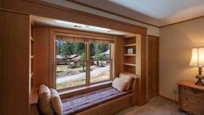 A room with a built-in bench under a large window, wooden shelves, and a lamp. - Scenic Wonders Apple Tree Home 3 Br (Yosemite National Park)