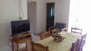 A dining area with a table, chairs, a television, and a door leading to another room. - Aitue Departamentos (Colon)