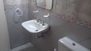 A bathroom with a white sink, a toilet, and a shower. - Aitue Departamentos (Colon)