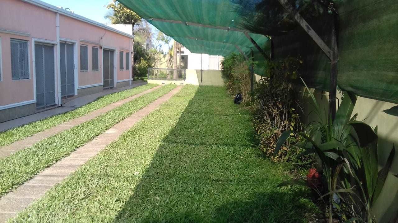 Un espacio cubierto de césped con un sendero que conduce a un edificio con varias puertas.
