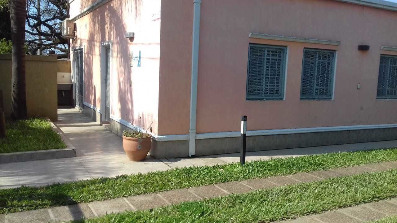 Un edificio con fachada rosa, un camino de hormigón y una zona ajardinada.