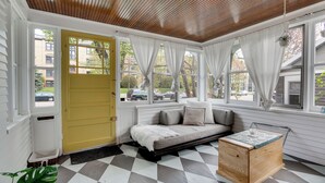 Um quarto aconchegante com piso xadrez, um banco de madeira e uma porta amarela.