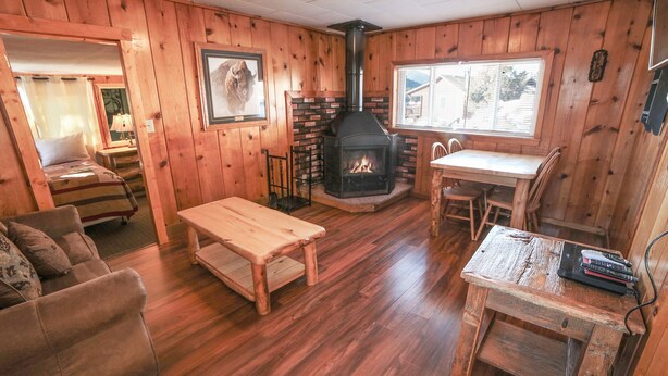 A cozy cabin interior with a fireplace, wooden furniture, and a window with blinds. - Charming Two bedroom Cabin, Dog Friendly close to National Park (Estes Park)