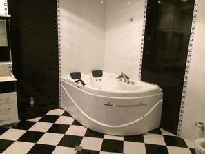 Een bad/douchecombinatie, een bubbelbad, een haardroger, handdoeken