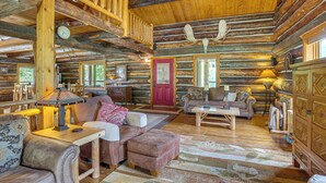 A log cabin interior with a wooden staircase, a red door, and a fireplace. - Log Home on 40-Acre Crested Butte Ranch (Crested Butte)