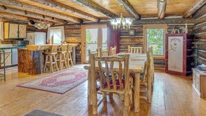 A log cabin interior with a dining area, kitchen, and a large wooden door. - Log Home on 40-Acre Crested Butte Ranch (Crested Butte)