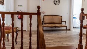 Una escalera de madera con barandilla, un sofá estampado y un reloj de pared.