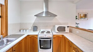 Eine kleine Küche mit Gasherd, Backofen, Mikrowelle und einer Edelstahl-Dunstabzugshaube.