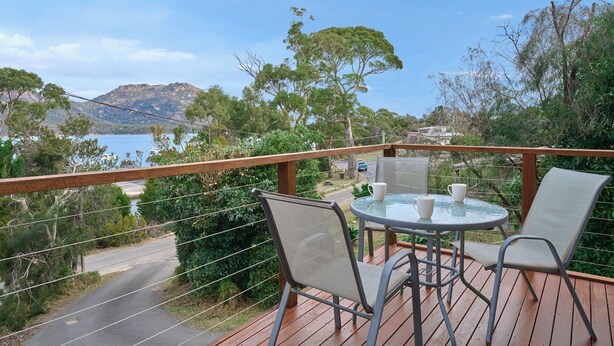 Eine Terrasse mit Tisch und Stühlen mit Blick auf eine malerische Seen- und Berglandschaft.