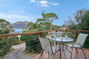 Une terrasse avec une table et des chaises offrant une vue panoramique sur un lac et des montagnes.