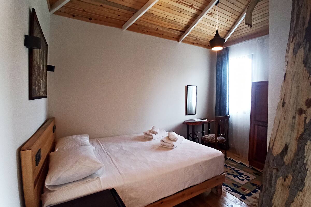 A bedroom with a wooden bed, a small table, and a chair.