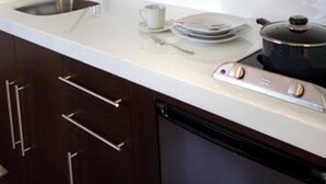 A kitchen with a sink, a coffee cup, a stack of plates, and a pot. - Suites Londres 212 (Mexico City)