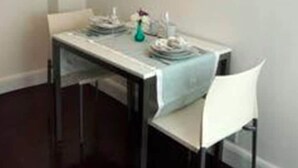 A dining area with a table set for two, a modern pendant light, and a white chair. - Suites Londres 212 (Mexico City)