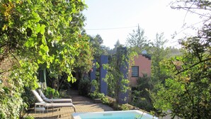 Un patio trasero con piscina, sillas de descanso y una zona ajardinada.